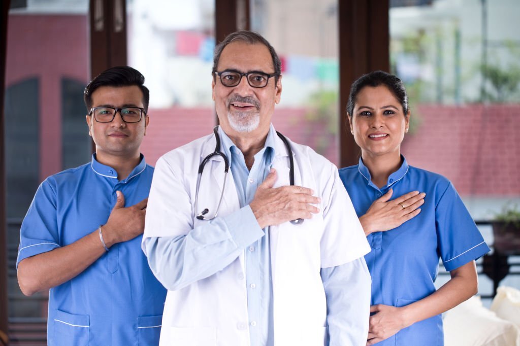 Positive doctor and nursing staff with hands on chest